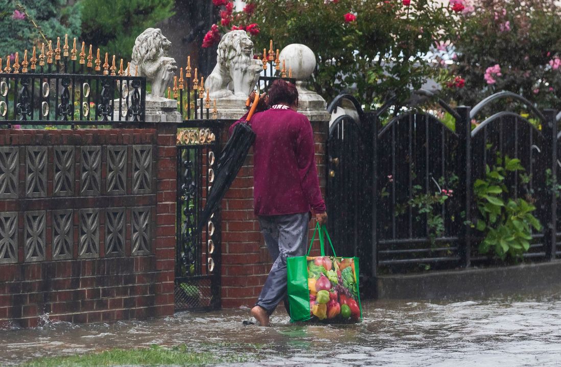 A person navigates a flooded sidewalk in Queens
